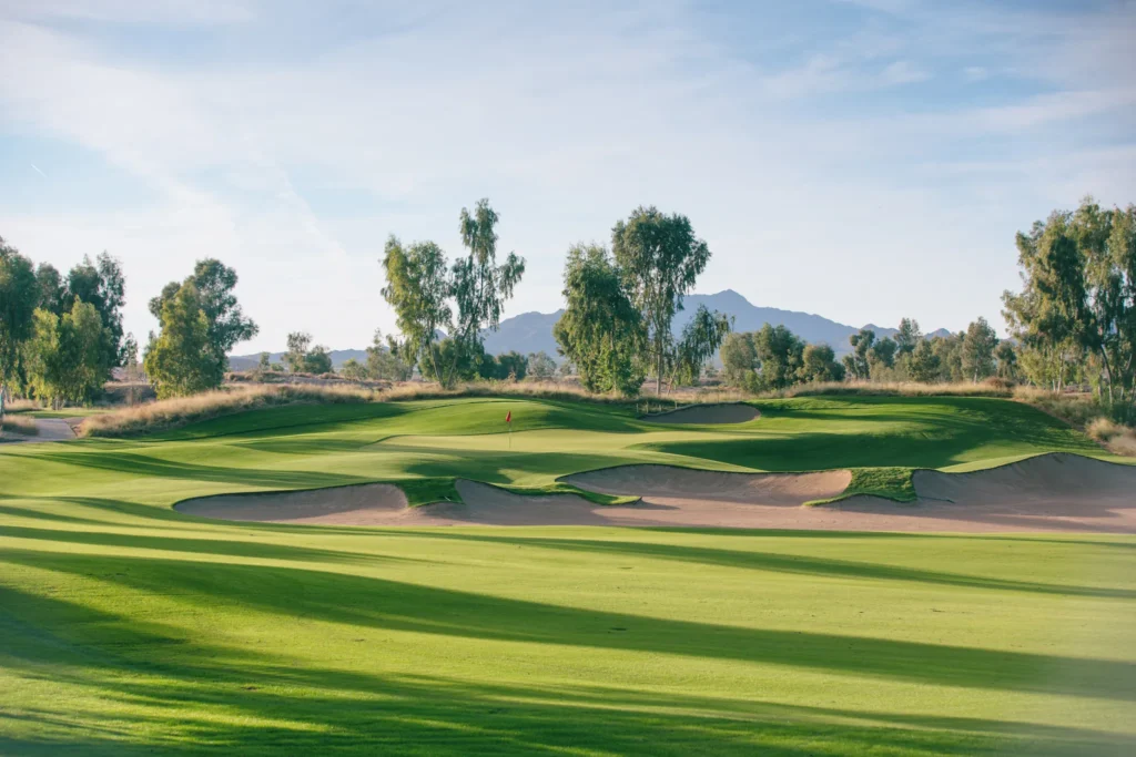 Ak-Chin Southern Dunes fairway leading to a green framed by bunkers, with mountains behind