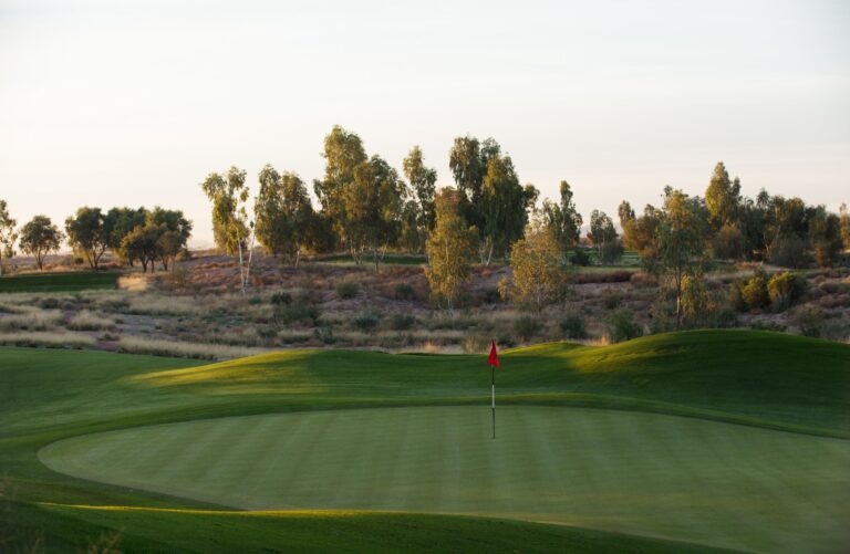 Late afternoon light on an Ak-Chin Southern Dunes green with flagstick and eucalyptus trees