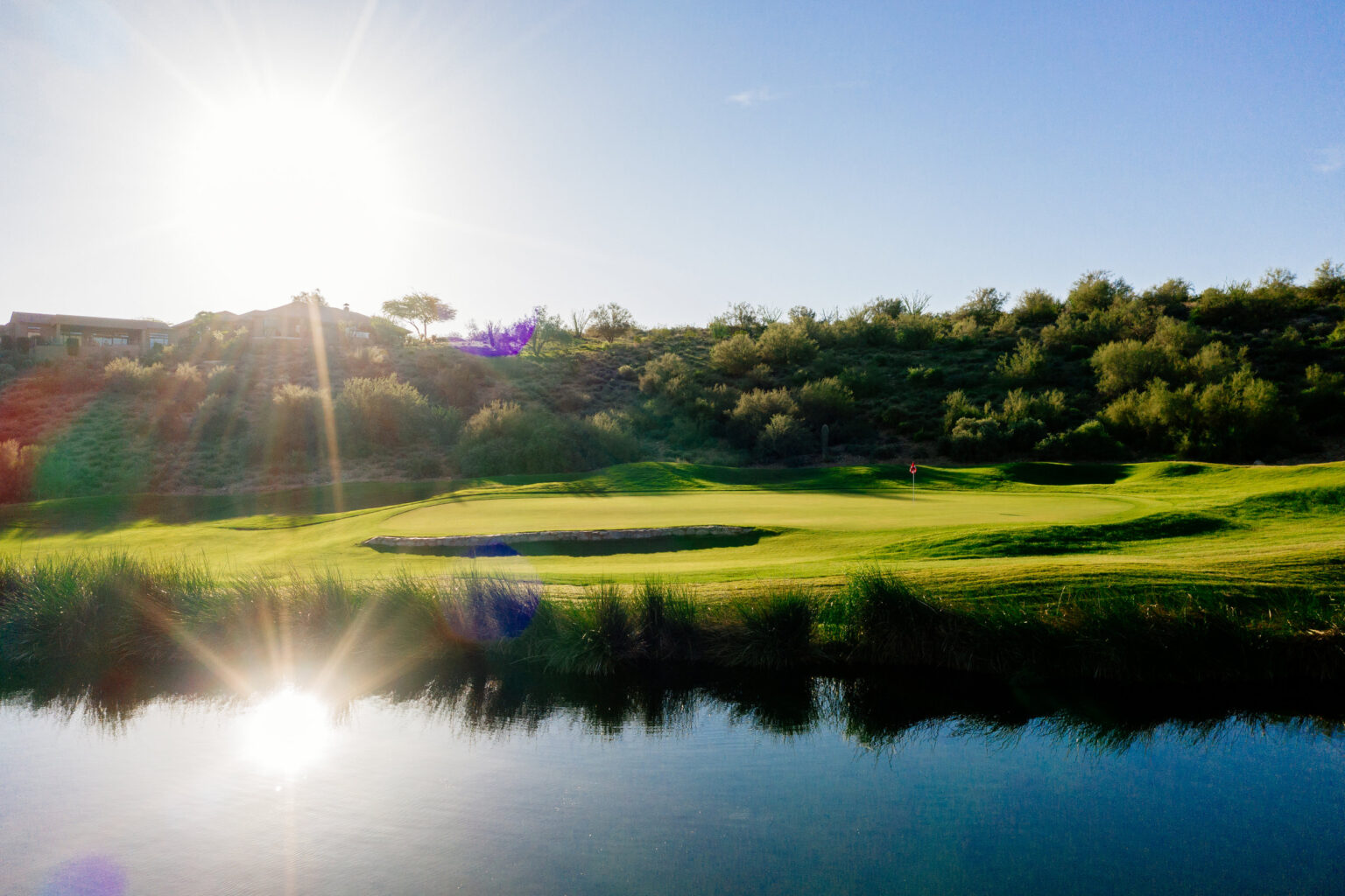SunRidge Canyon green beside water with the sun low over the McDowell Mountains