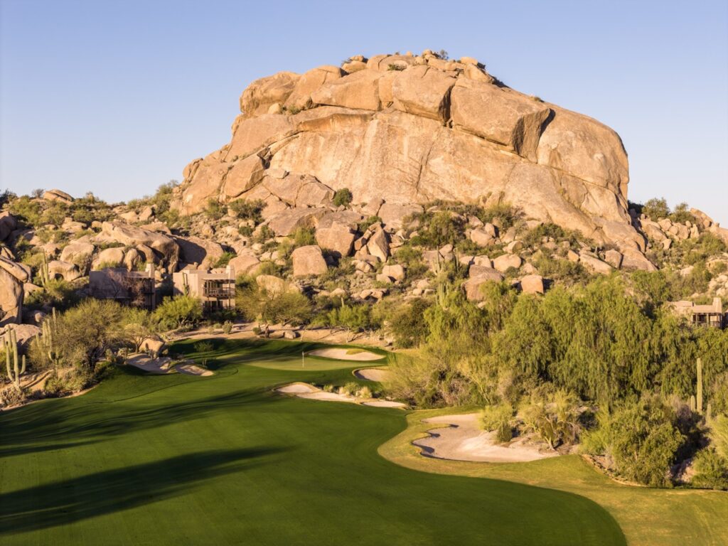 Green set below a towering boulder pile at The Boulders Golf Club