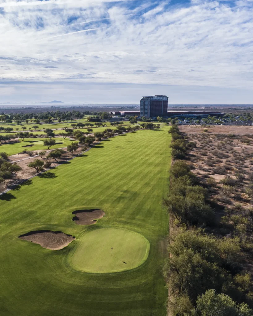 Full view of an O'odham Course fairway at Talking Stick Golf Club from tee to green, with the Talking Stick Resort tower beyond