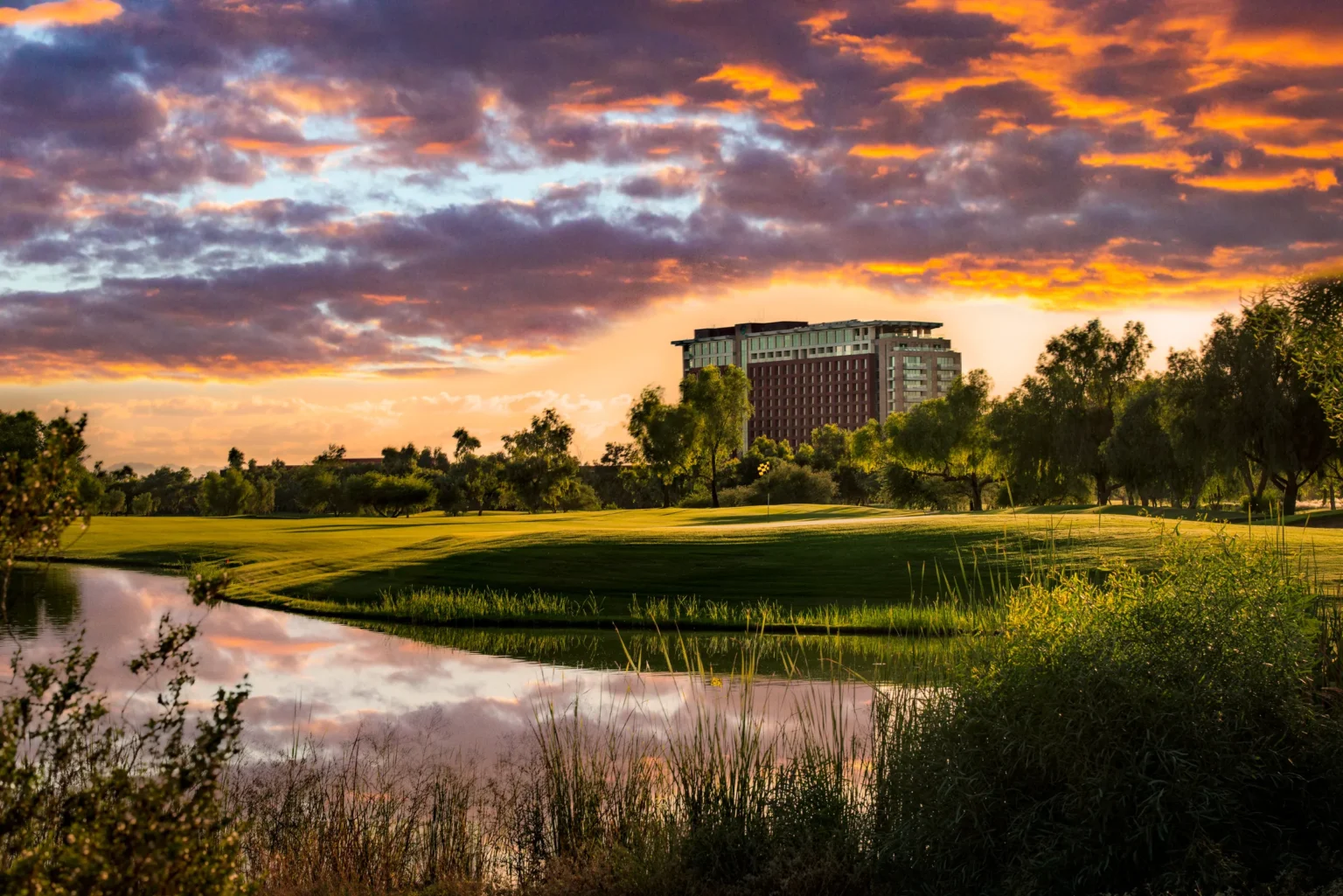 Hole 17 on the Piipaash Course at sunset with Talking Stick Resort beyond the water, Scottsdale Arizona