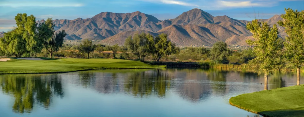 Lake and green on hole 18 of the Piipaash Course at Talking Stick Golf Club with Red Mountain behind